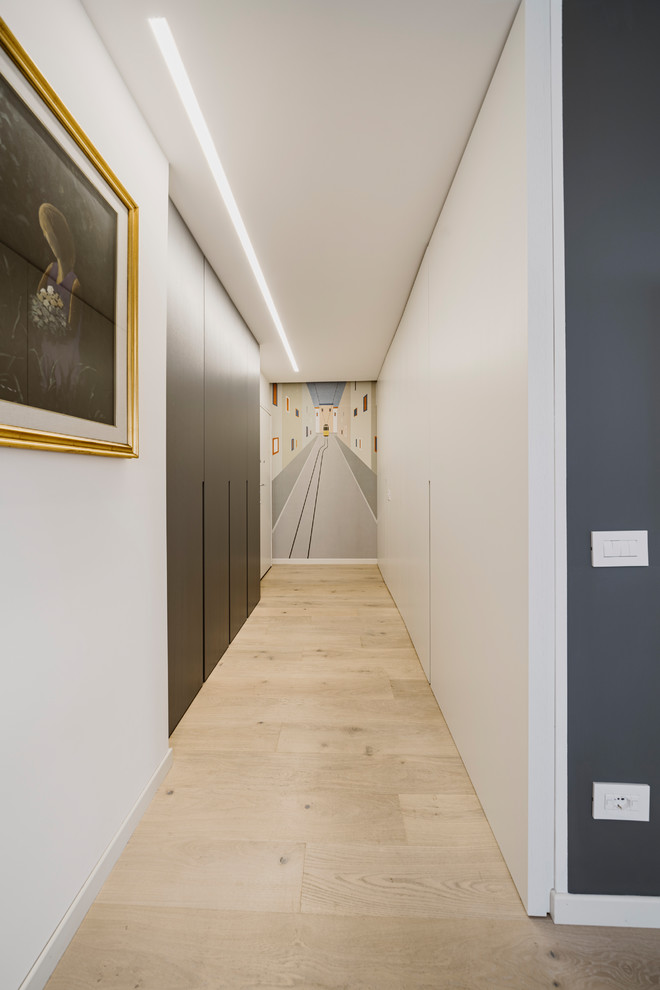 Exemple d'un couloir moderne avec un mur blanc, parquet clair et un sol beige.