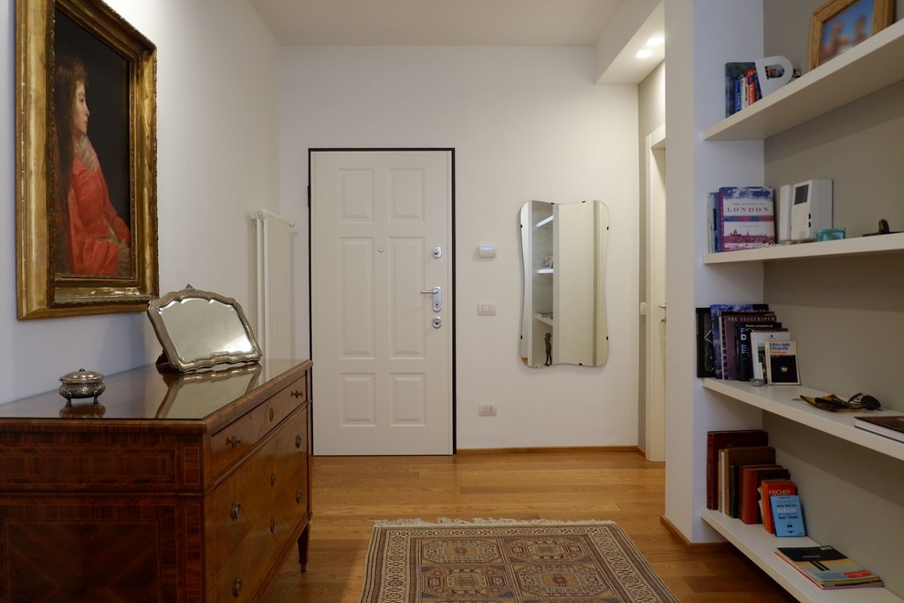 Idées déco pour un hall d'entrée contemporain de taille moyenne avec un sol en bois brun, une porte simple et une porte blanche.