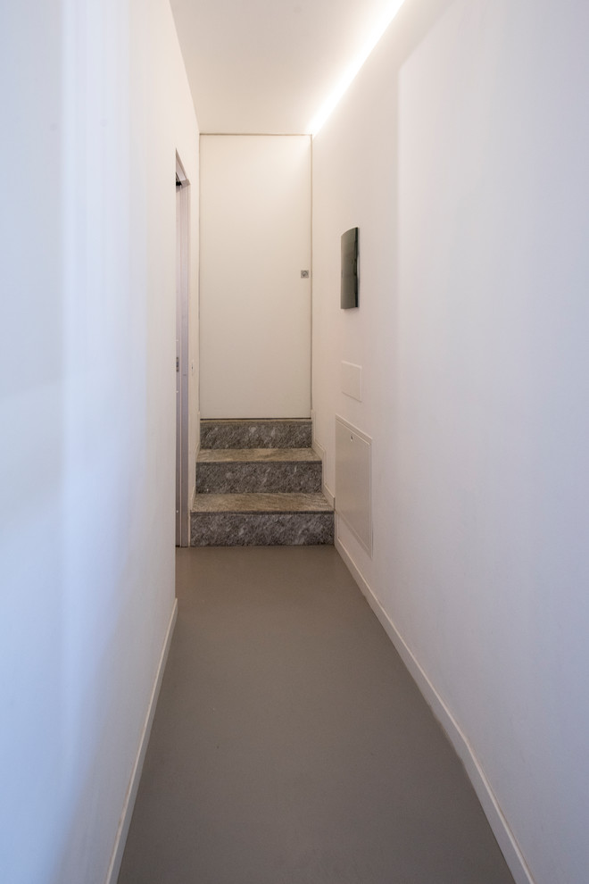 ミラノにある高級な中くらいなコンテンポラリースタイルのおしゃれな廊下 (白い壁、コンクリートの床、グレーの床) の写真