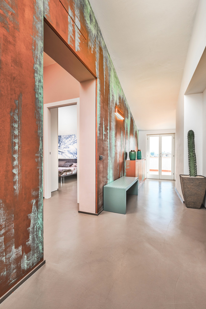 На фото: большая узкая прихожая в современном стиле с разноцветными стенами, бетонным полом, одностворчатой входной дверью, белой входной дверью и серым полом