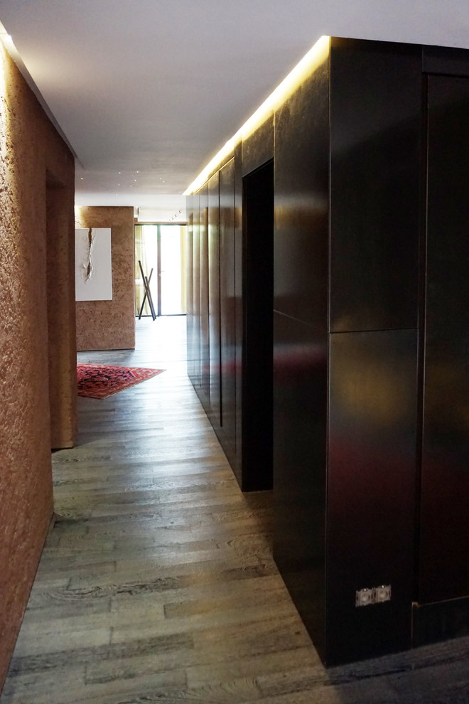 他の地域にある巨大なインダストリアルスタイルのおしゃれな廊下 (茶色い壁、濃色無垢フローリング、グレーの床) の写真