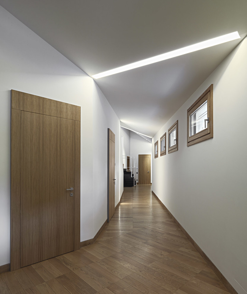 Foto de recibidores y pasillos actuales de tamaño medio con paredes blancas y suelo de madera en tonos medios