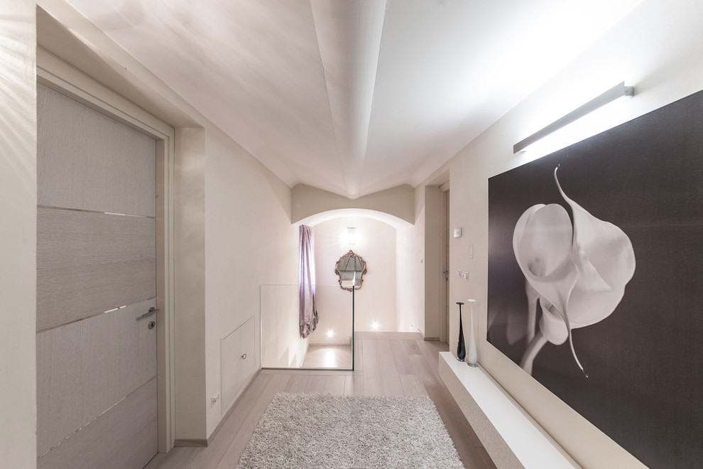 Aménagement d'un grand couloir contemporain avec un mur blanc et parquet clair.