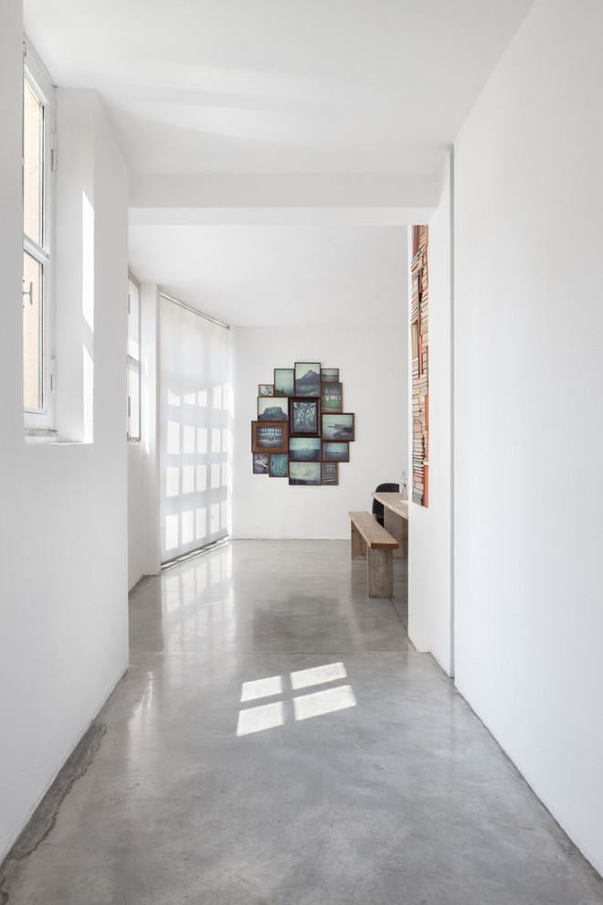 На фото: коридор в современном стиле с белыми стенами и бетонным полом с