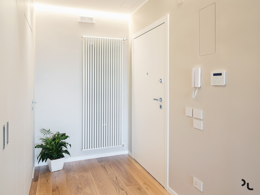 Idee per un piccolo ingresso moderno con pareti grigie, parquet chiaro, una porta singola, una porta bianca e pavimento beige