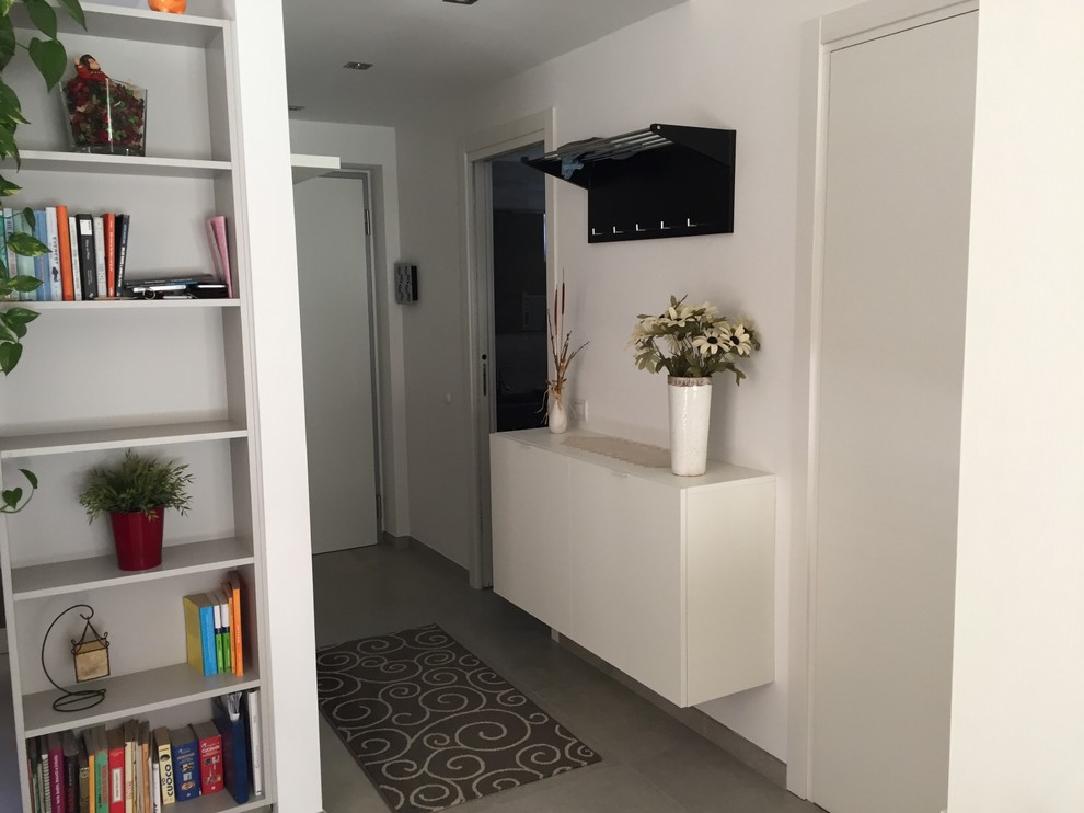 Immagine di un piccolo ingresso minimalista con pareti bianche, pavimento con piastrelle in ceramica e pavimento grigio