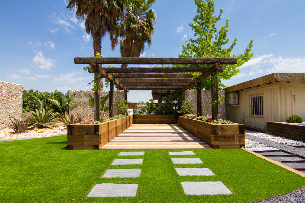 Foto di un grande giardino tropicale esposto in pieno sole davanti casa con un ingresso o sentiero e pavimentazioni in pietra naturale