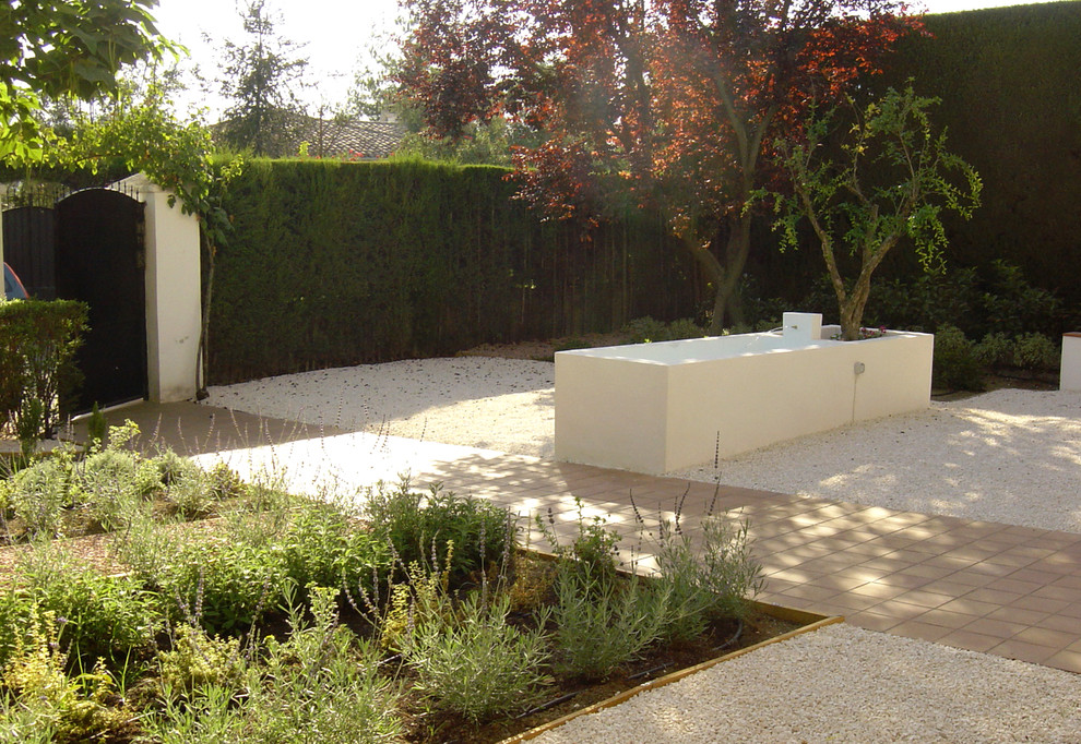 Diseño de jardín de secano actual de tamaño medio en patio delantero con fuente y exposición total al sol