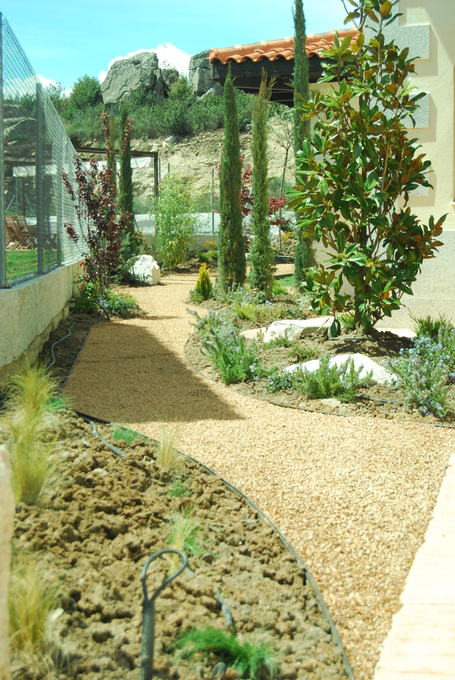 Imagen de acceso privado campestre de tamaño medio en primavera en patio lateral con gravilla y exposición parcial al sol