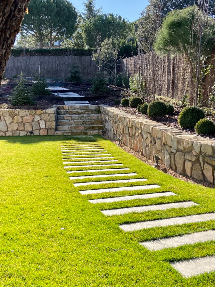 Esempio di un giardino design con recinzione in pietra