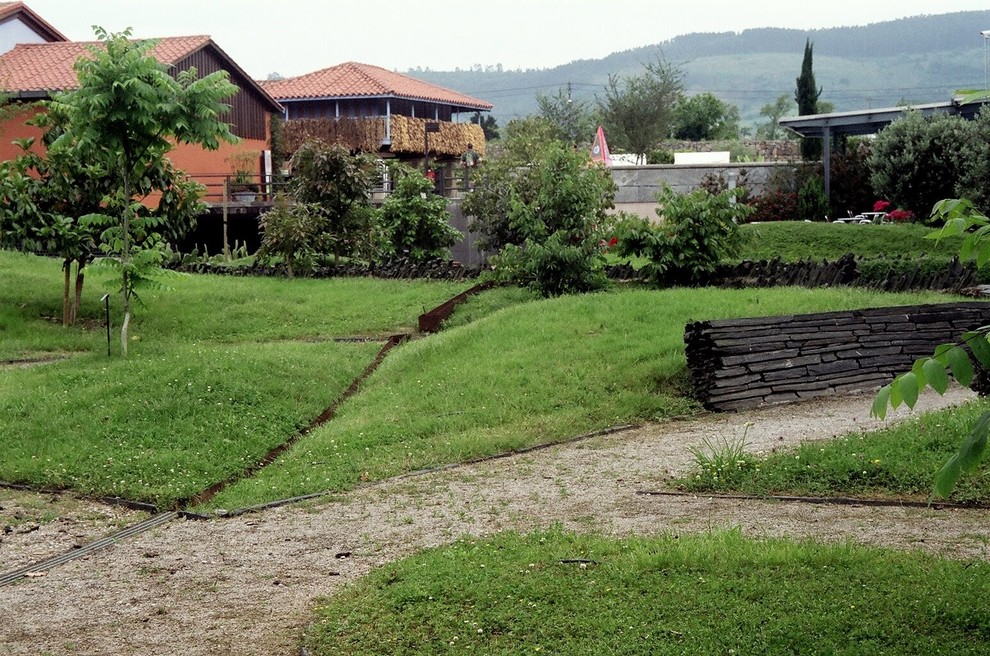 Immagine di un ampio giardino stile rurale esposto a mezz'ombra in estate con un muro di contenimento e ghiaia