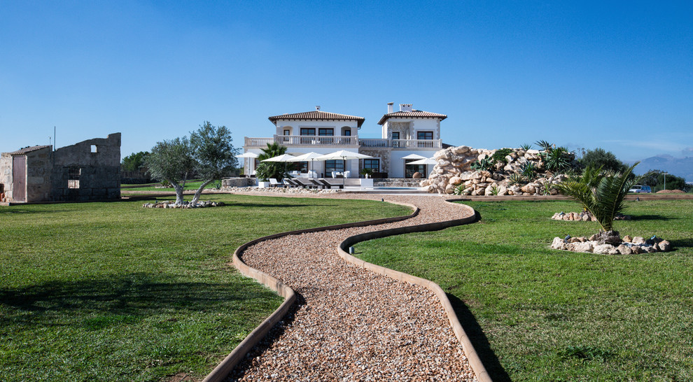 Esempio di un grande giardino xeriscape mediterraneo esposto in pieno sole davanti casa con un ingresso o sentiero e ghiaia