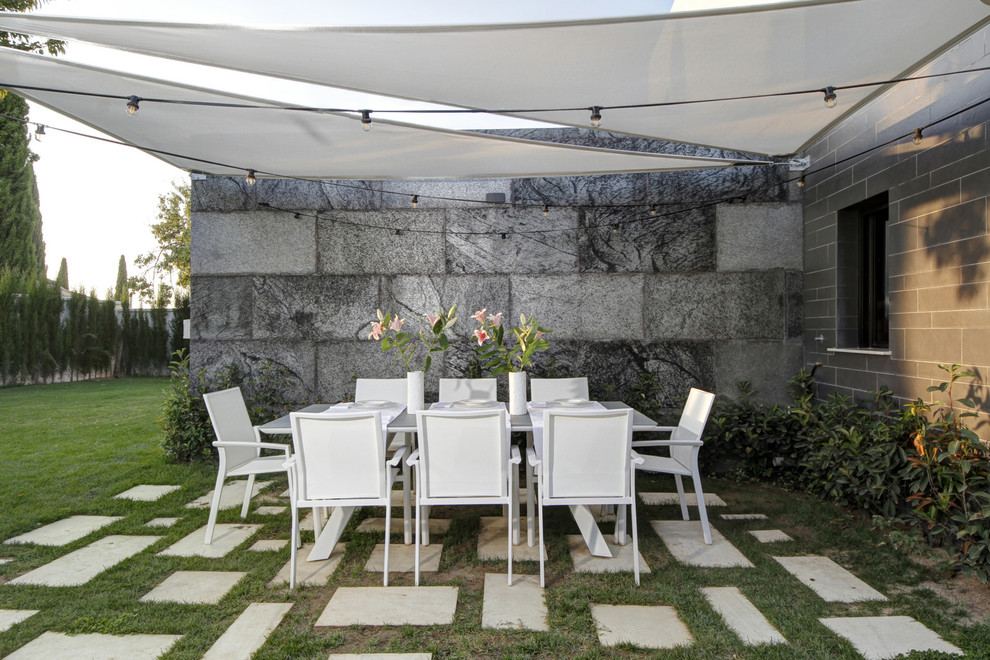 Diseño de patio minimalista en patio trasero con adoquines de hormigón