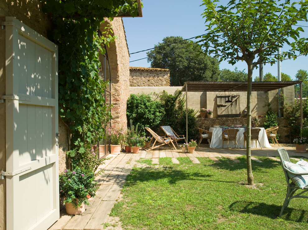 Cette image montre un jardin arrière rustique de taille moyenne avec une exposition partiellement ombragée et une terrasse en bois.