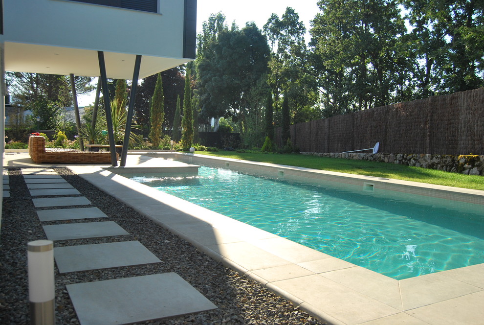 Diseño de acceso privado minimalista grande en verano en patio trasero con gravilla y exposición parcial al sol