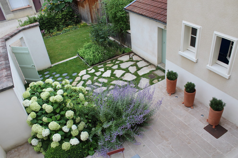 Réalisation d'un jardin champêtre de taille moyenne avec une exposition partiellement ombragée et des pavés en pierre naturelle.