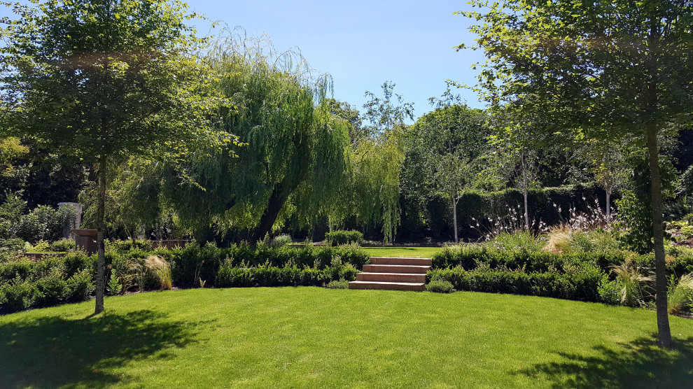 Geometrischer, Mittelgroßer Shabby-Look Garten im Frühling, hinter dem Haus mit Blumenbeet, direkter Sonneneinstrahlung und Natursteinplatten in Sonstige