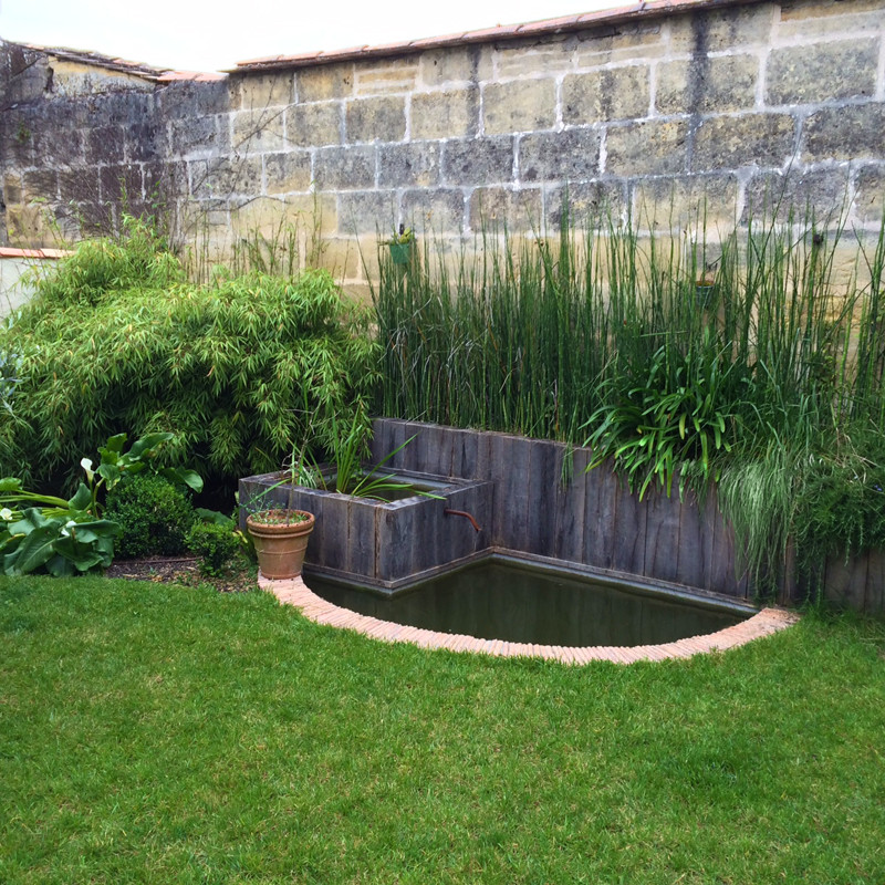Cette image montre un petit jardin latéral style shabby chic l'été avec un bassin, une exposition partiellement ombragée et un paillis.