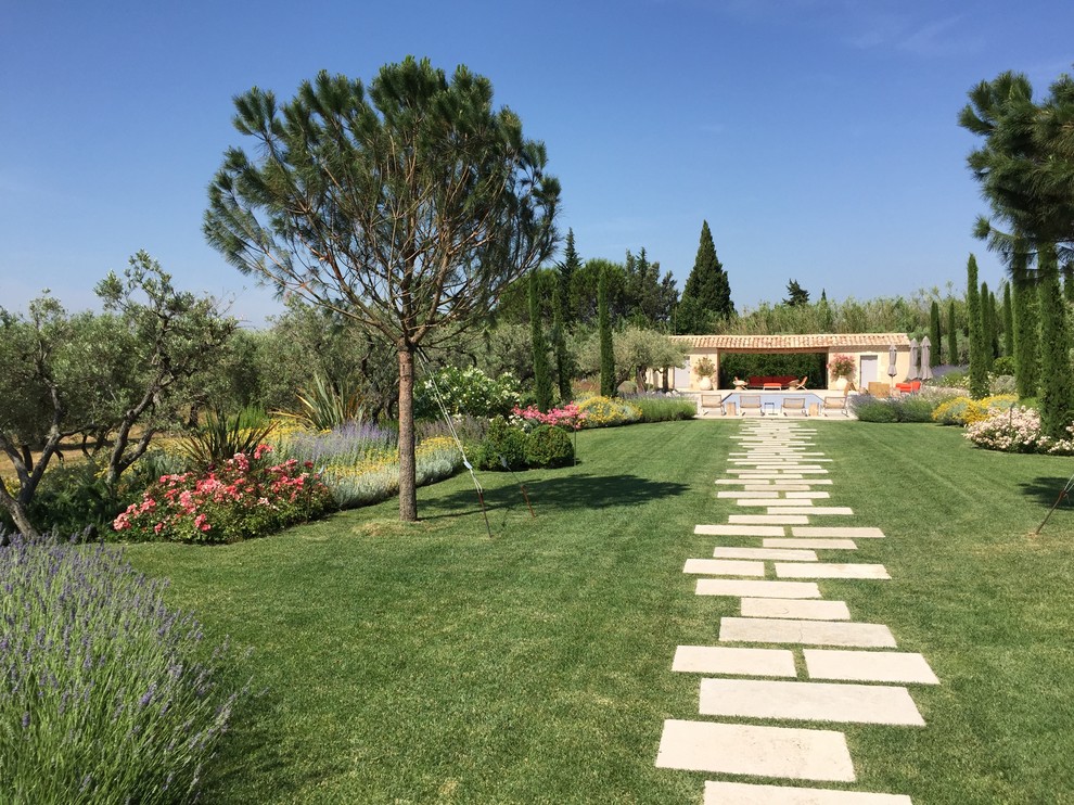 Modelo de camino de jardín mediterráneo extra grande en verano en patio trasero con exposición total al sol y adoquines de piedra natural