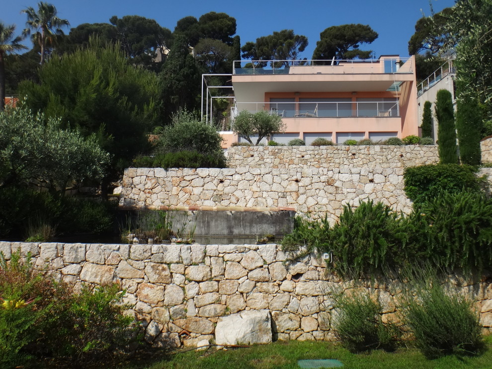 Ejemplo de jardín mediterráneo grande en patio trasero con muro de contención