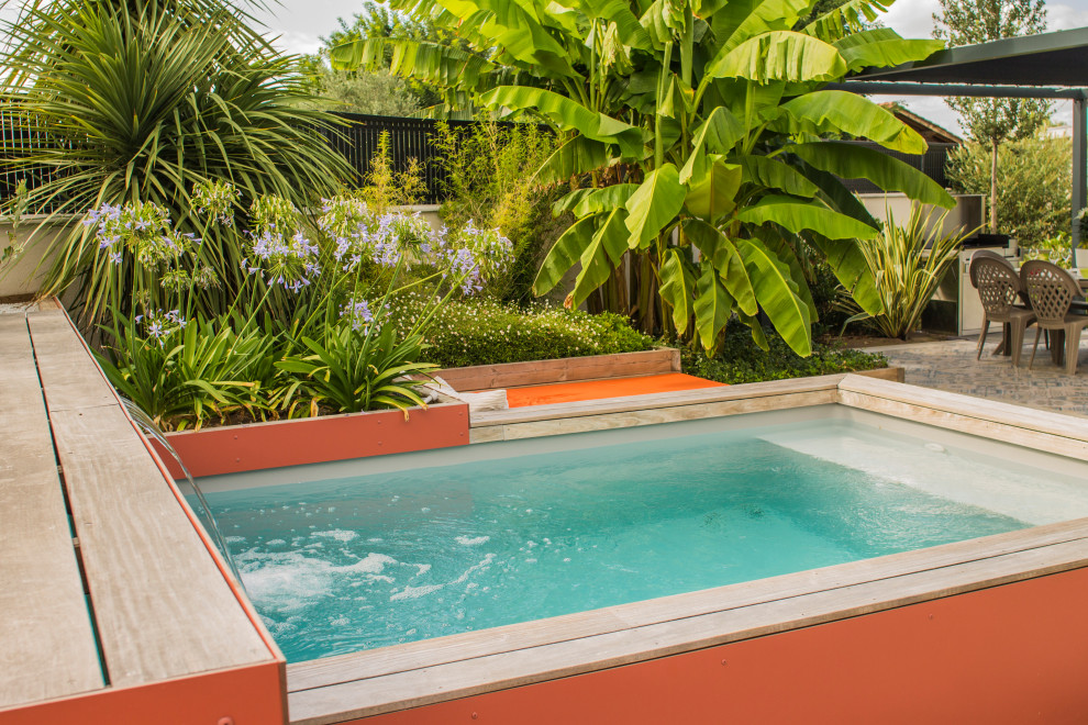 Diseño de piscina tropical pequeña rectangular en patio trasero con suelo de baldosas
