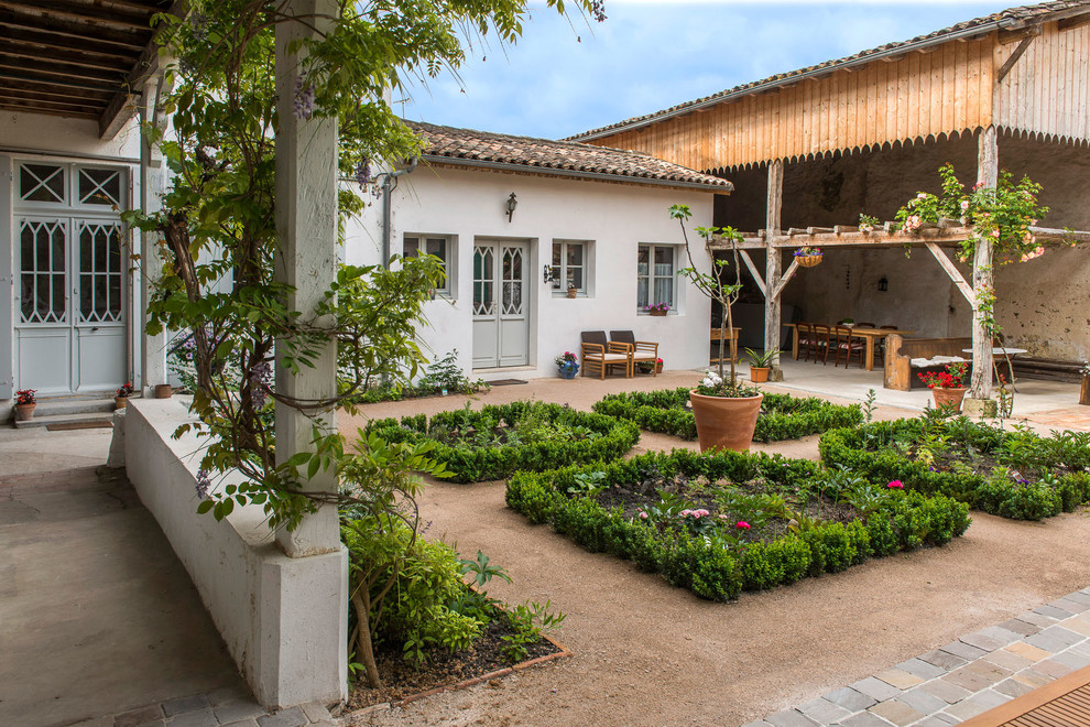 Imagen de jardín de estilo de casa de campo de tamaño medio en primavera en patio con gravilla, jardín francés, jardín de macetas y exposición total al sol