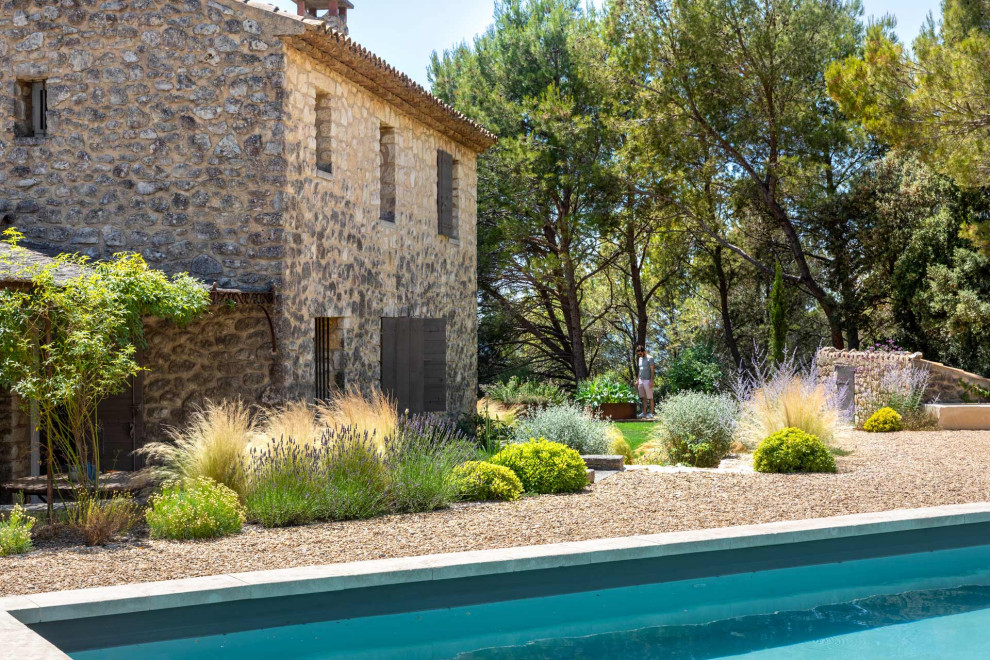 Источник вдохновения для домашнего уюта: большой солнечный участок и сад на заднем дворе в средиземноморском стиле с клумбами, хорошей освещенностью и покрытием из гравия