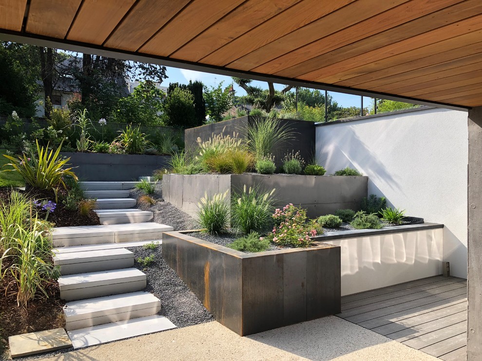Inspiration pour un jardin arrière design avec un mur de soutènement, une exposition partiellement ombragée et des pavés en béton.