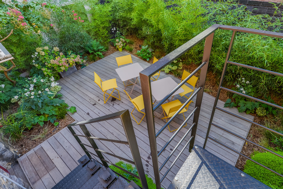 Cette image montre un petit jardin arrière design au printemps avec une exposition partiellement ombragée, une terrasse en bois et une clôture en métal.