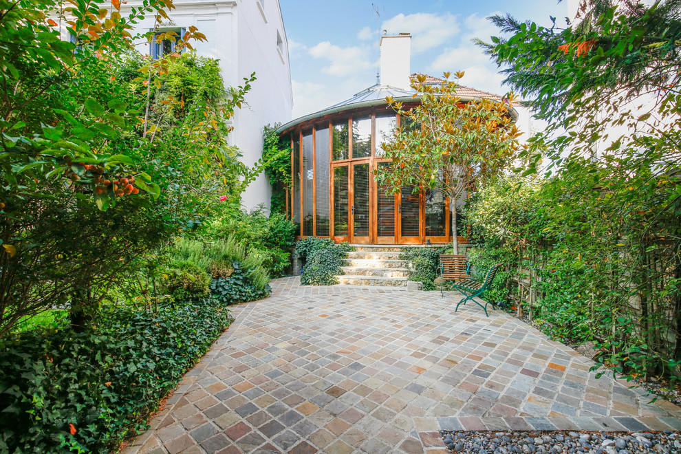 Immagine di un grande giardino formale tradizionale esposto a mezz'ombra davanti casa in primavera con un ingresso o sentiero, pavimentazioni in pietra naturale e recinzione in pietra