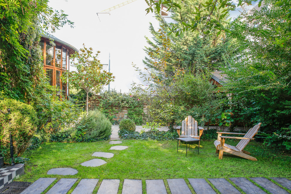 На фото: большой весенний регулярный сад на переднем дворе в классическом стиле с полуденной тенью, покрытием из каменной брусчатки и с каменным забором с