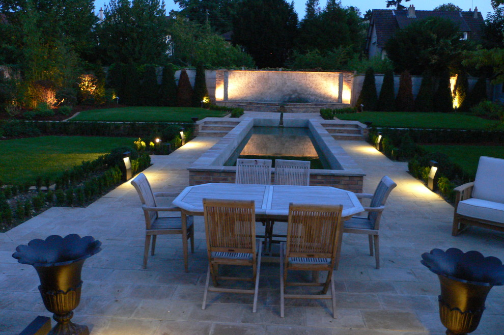 Diseño de patio clásico grande en patio trasero con adoquines de hormigón