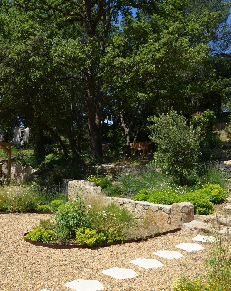Modelo de jardín mediterráneo grande en patio delantero con exposición parcial al sol y gravilla