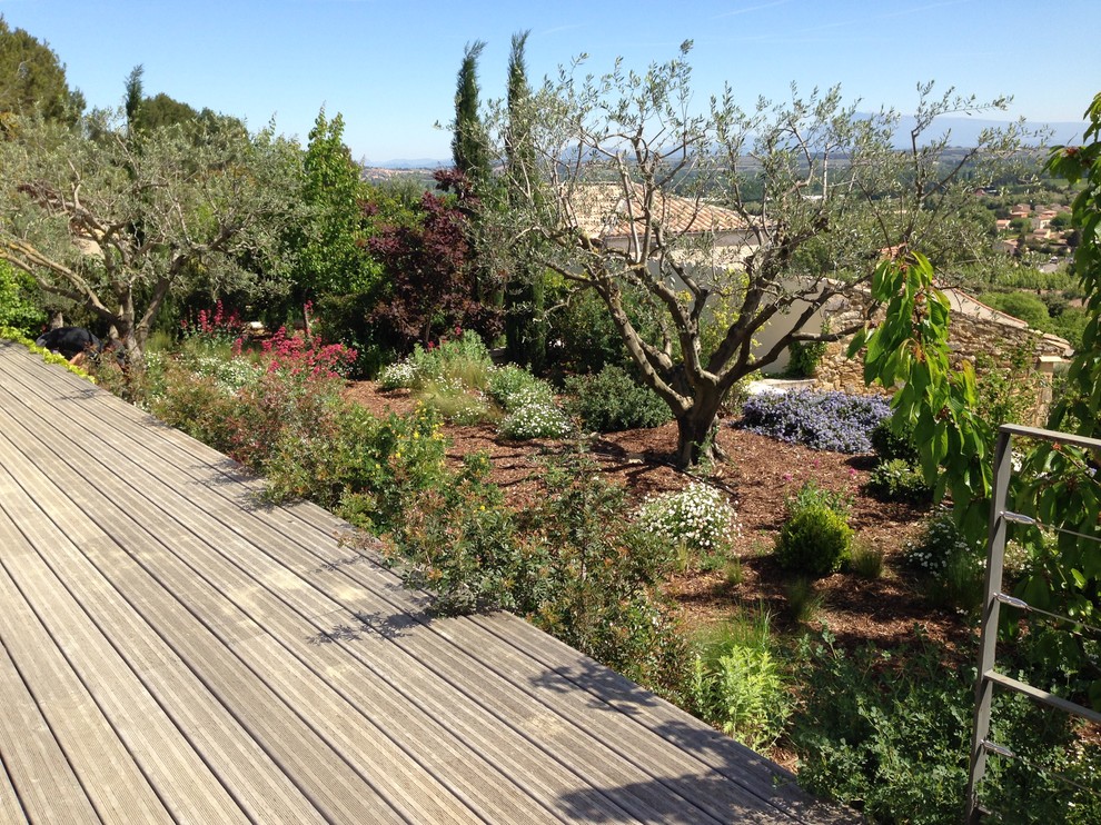 Cette image montre un jardin arrière méditerranéen de taille moyenne et au printemps avec une exposition ensoleillée et une terrasse en bois.