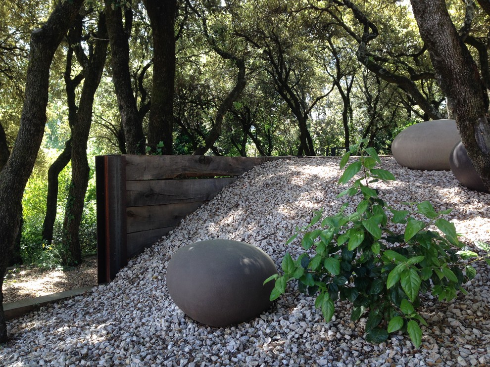 Cette image montre un petit jardin méditerranéen avec un mur de soutènement, une exposition partiellement ombragée et du gravier.
