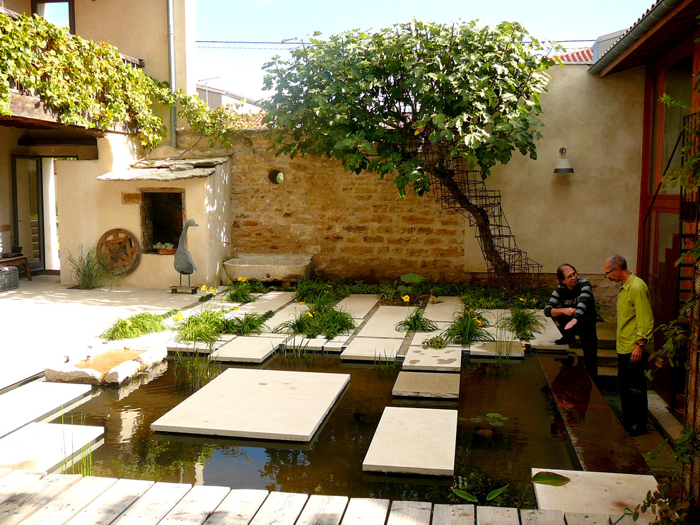 This is an example of a small modern courtyard partial sun garden for summer in Lyon with a water feature and decking.