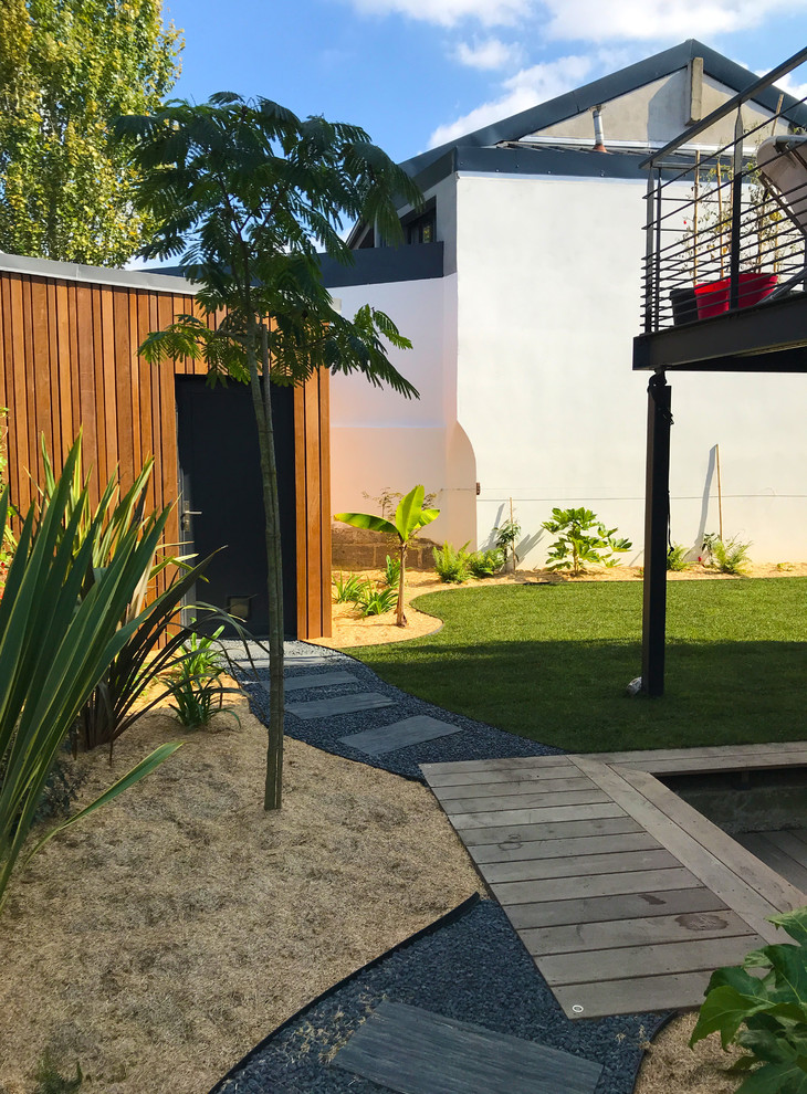 Ispirazione per un giardino xeriscape tropicale esposto a mezz'ombra di medie dimensioni e nel cortile laterale in estate con un ingresso o sentiero e ghiaia