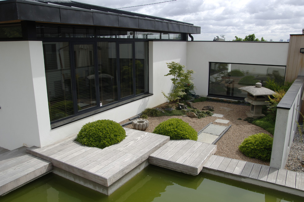 Aménagement d'un grand jardin arrière asiatique au printemps avec un bassin, une exposition ensoleillée et une terrasse en bois.