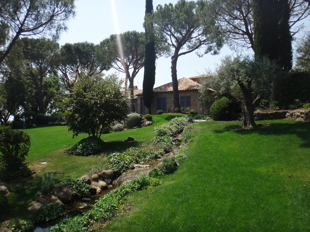 На фото: большой садовый фонтан на заднем дворе в средиземноморском стиле с