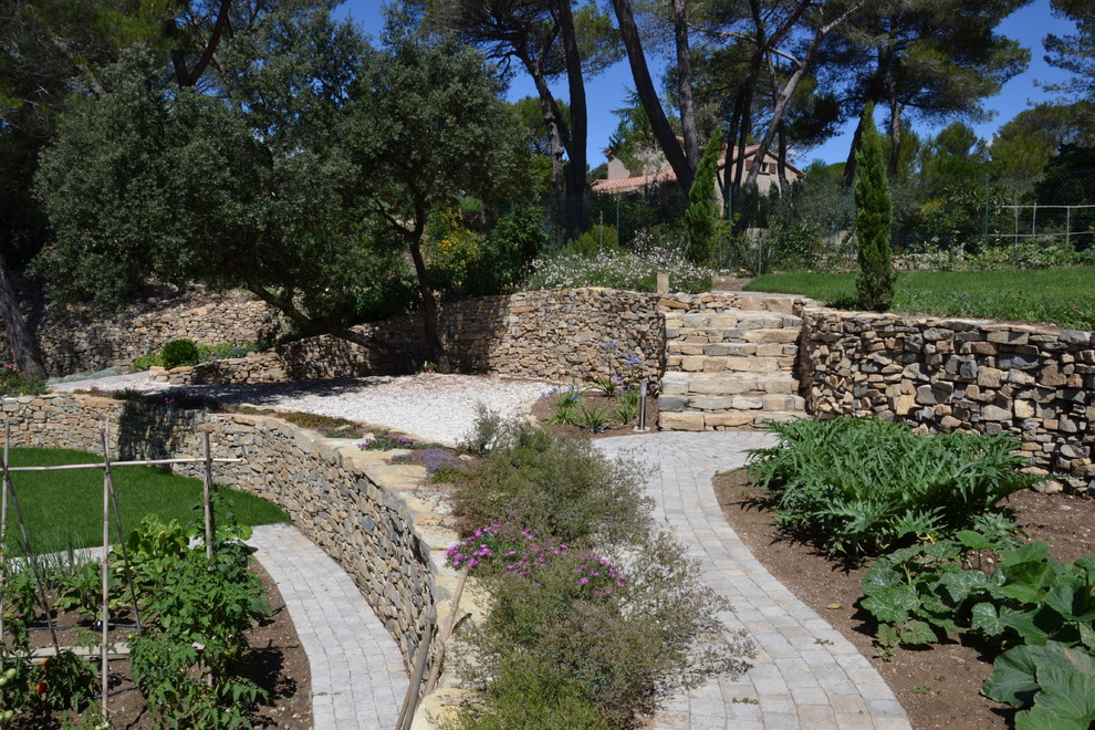 Inspiration för en stor medelhavsstil trädgård i full sol i slänt på sommaren, med en köksträdgård och naturstensplattor