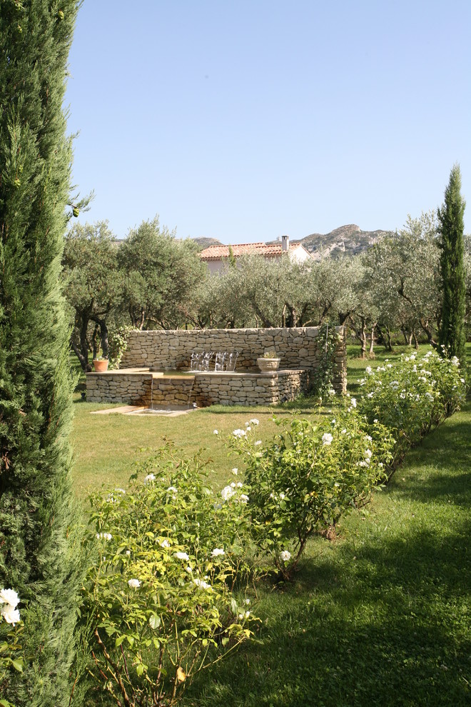 Großer Mediterraner Garten im Frühling, hinter dem Haus mit Wasserspiel und direkter Sonneneinstrahlung in Sonstige