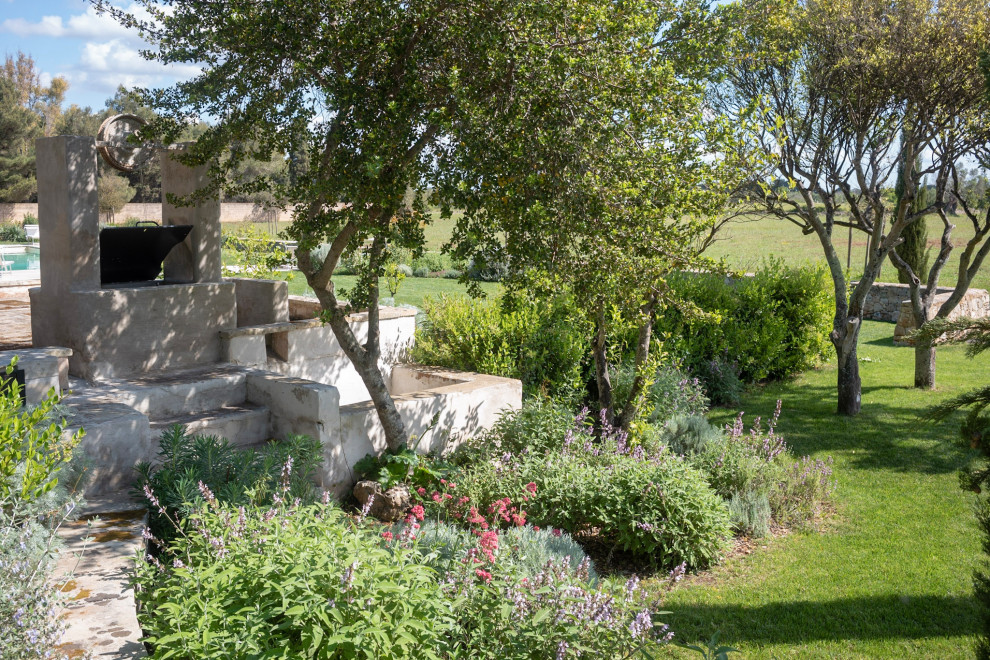 Идея дизайна: большой солнечный, весенний засухоустойчивый сад на заднем дворе в средиземноморском стиле с клумбами, хорошей освещенностью и покрытием из каменной брусчатки