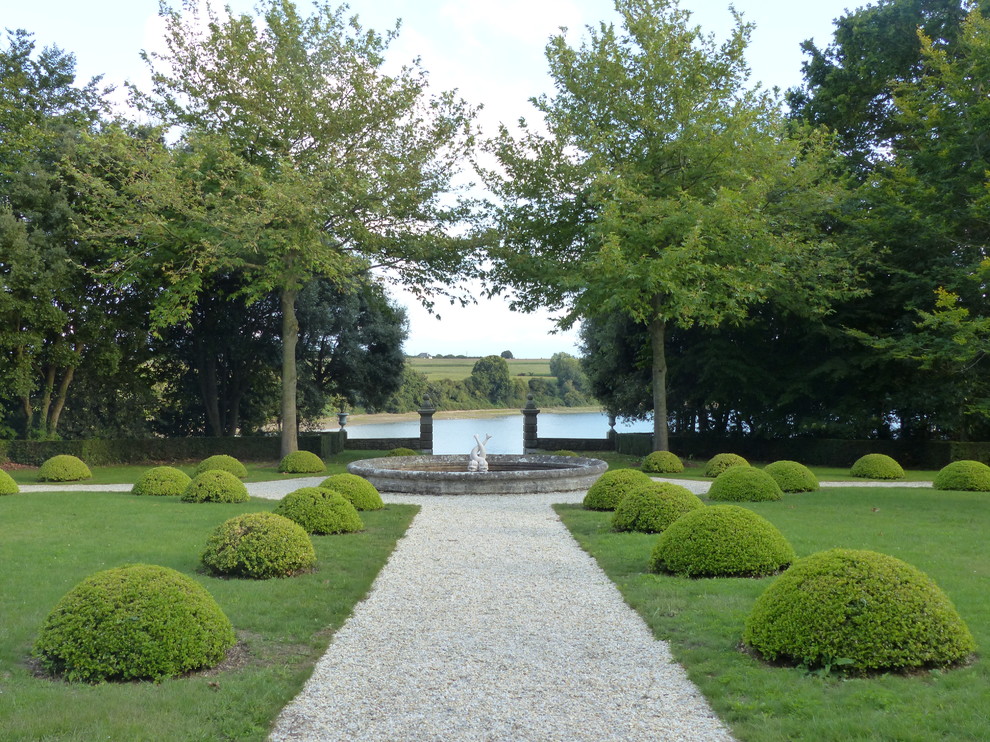 Immagine di un ampio giardino formale tradizionale esposto a mezz'ombra in cortile in estate con ghiaia e un ingresso o sentiero