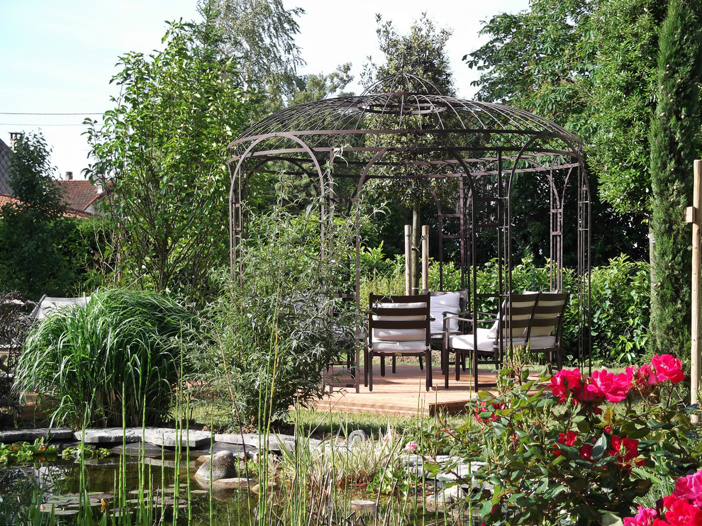Exemple d'un jardin à la française arrière nature de taille moyenne avec un bassin, une exposition ensoleillée et une terrasse en bois.