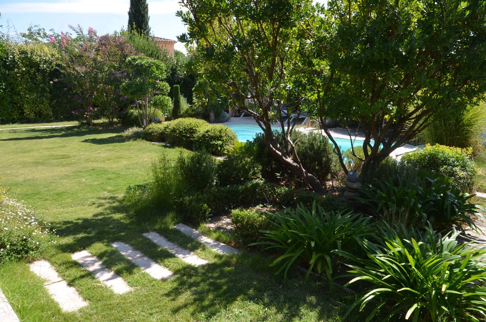Ejemplo de jardín actual grande en patio delantero con exposición total al sol y adoquines de piedra natural