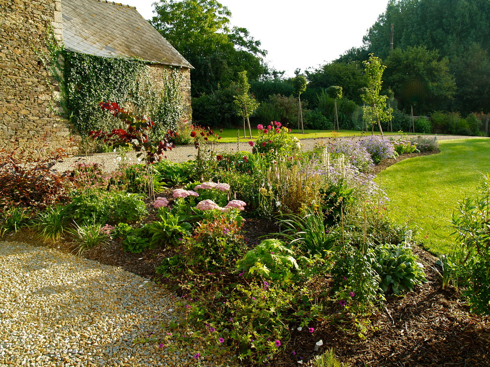 Modelo de jardín de estilo de casa de campo en primavera con gravilla y parterre de flores