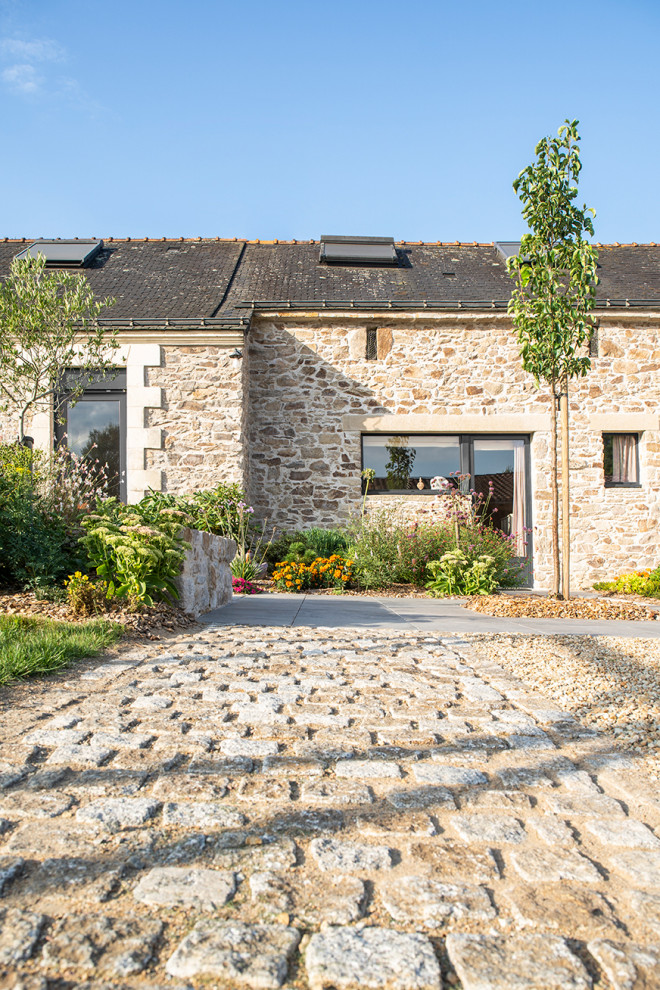 Diseño de jardín de estilo de casa de campo de tamaño medio en primavera en patio delantero con roca decorativa, exposición parcial al sol y adoquines de piedra natural