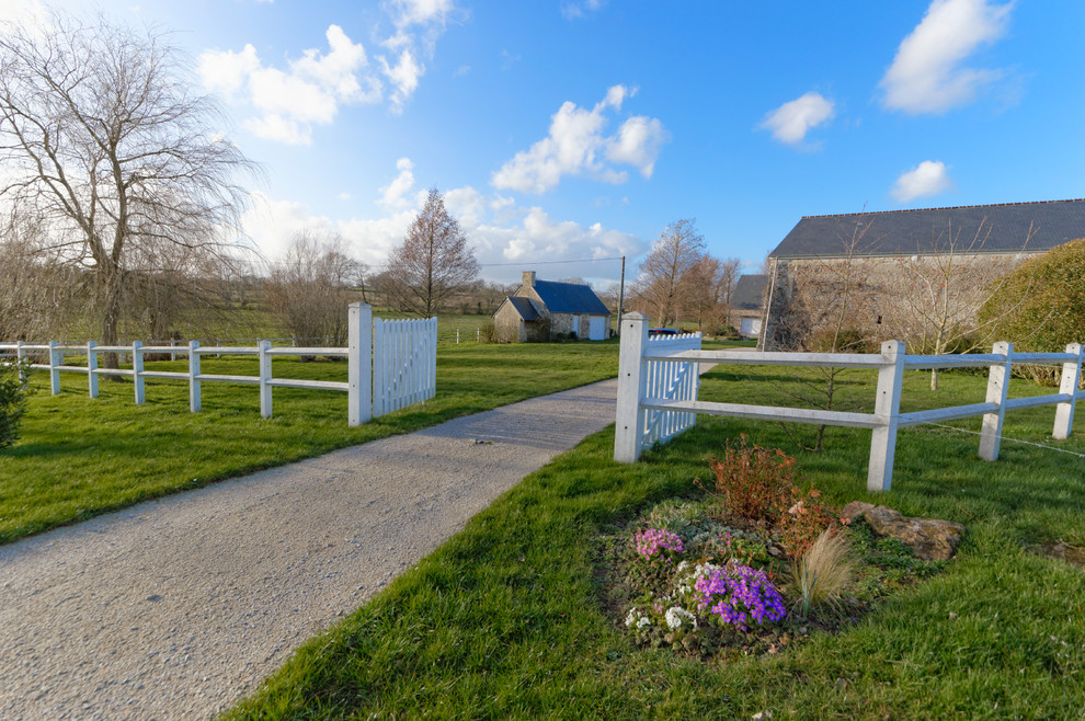 Inspiration for an expansive farmhouse front driveway full sun garden fence in Le Havre with gravel.