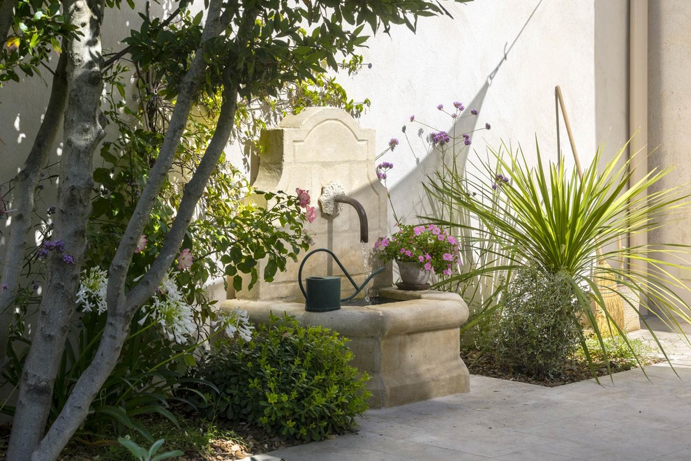 Réalisation d'un jardin méditerranéen avec un point d'eau et des pavés en pierre naturelle.