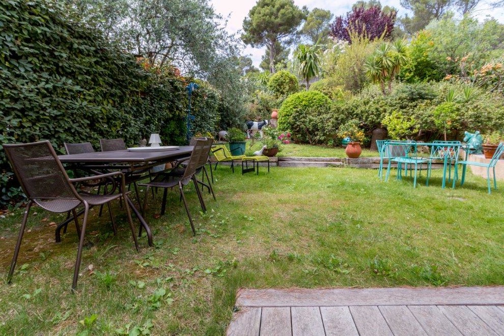 Großer Stilmix Garten im Sommer, hinter dem Haus mit Kübelpflanzen, direkter Sonneneinstrahlung und Dielen in Paris